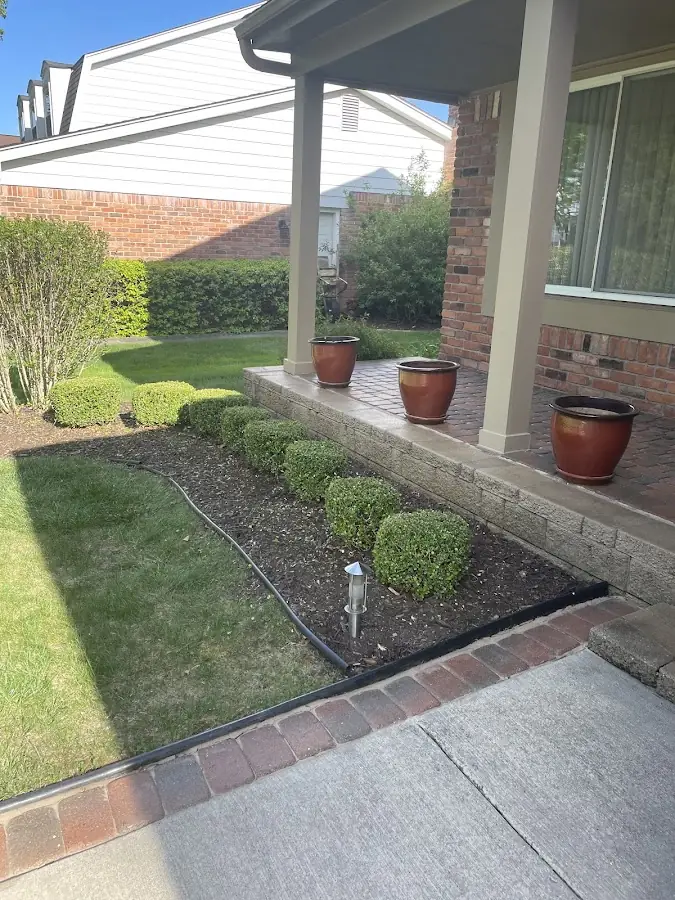 Landscaped front yard with garden bed and trimmed bushes at a Troy, MI home